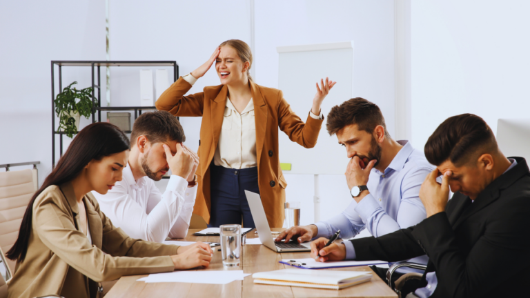 A business owner at a conference table with managers presenting problems for approval.