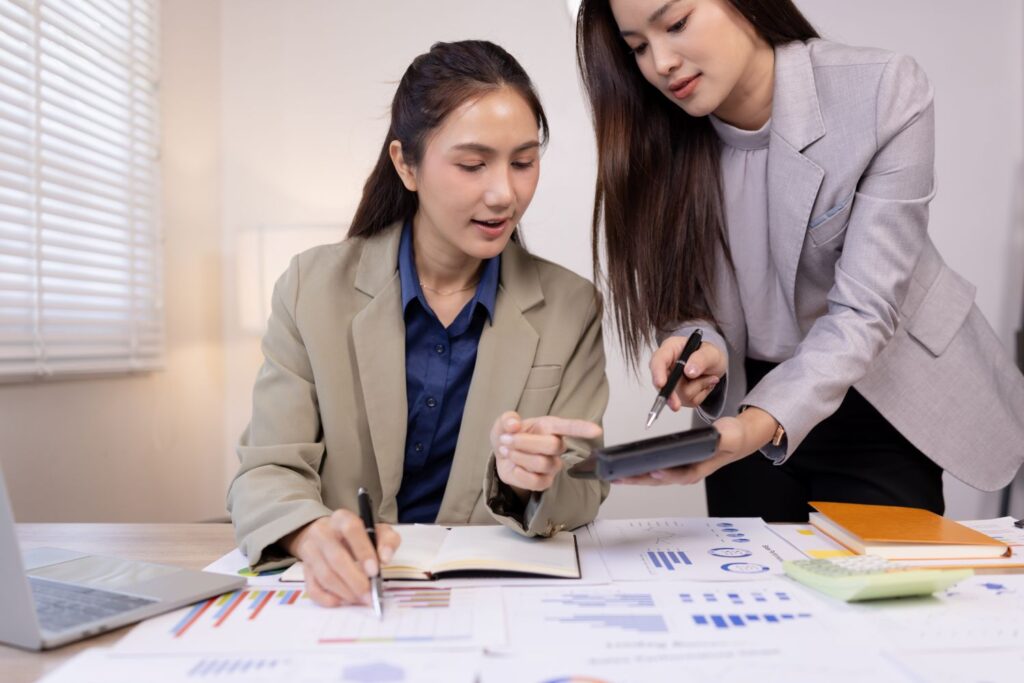 Manager and new hire seated at a desk reviewing a structured plan together, small business office setting