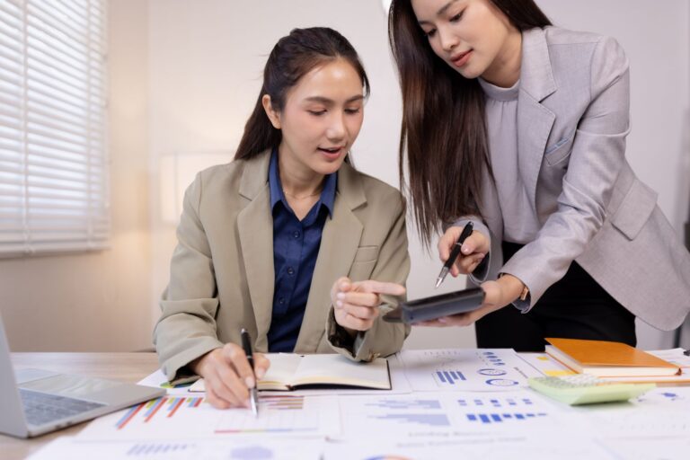 Manager and new hire seated at a desk reviewing a structured plan together, small business office setting