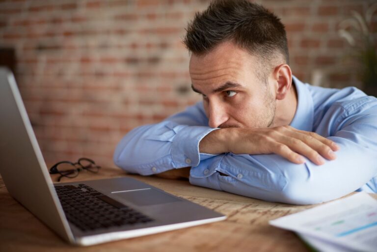 Business owner at whiteboard surrounded by sticky notes, clearly overwhelmed, team in background waiting for direction