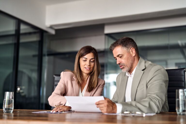 Manager and employee sitting together reviewing a printed job responsibilities document at a small business office